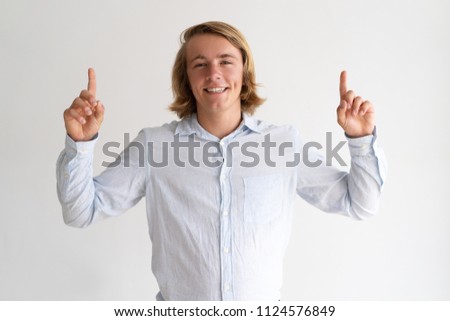 Happy young man pointing both forefingers upwards. Attractive guy recommending something. Recommendation concept. Isolated front view on white background.