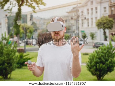 A young man plays a game wearing virtual reality glasses on the street. VR headset