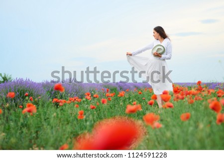 young woman is in the lavender field, beautiful summer landscape with red poppy flowers