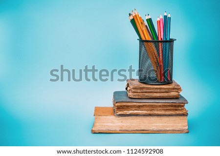 book and colorful pencils on wooden table