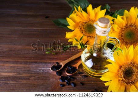 Organic sunflower oil in a small glass jar with sunflower seeds and fresh flowers.