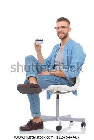Young man sitting on chair and holding credit card. Startupper. Young entrepreneur.