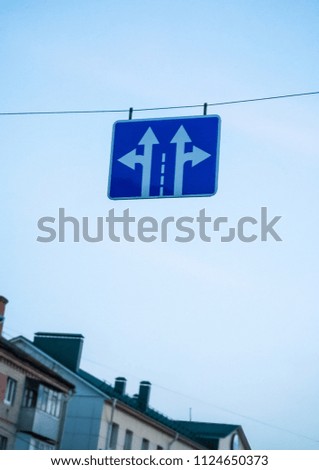 The traffic sign is hanging on a stretched over the road cable.