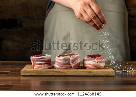 Adding salt by chef hands. Cooking beef steak fillet mignon with bacon. Steps process.