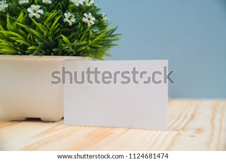 Blank business cards and little decorative tree in white vase on wooden working table with copy space for add text ID. and logo, business company concept idea.