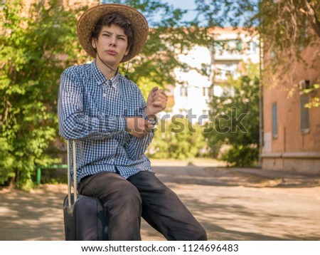 portrait young man sit in baggage case walking in europe city street on a summer vacation