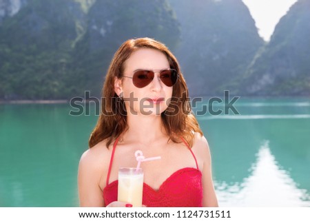 young woman on boat enjoying with glass of juice among the islands
