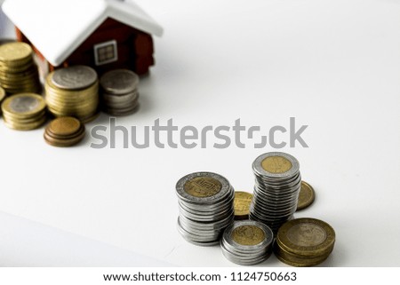 Mortgage loan and real estate tax macro financial Concept, Scandinavian house model and pile of coins money on white background with copy space in middle of the frame.