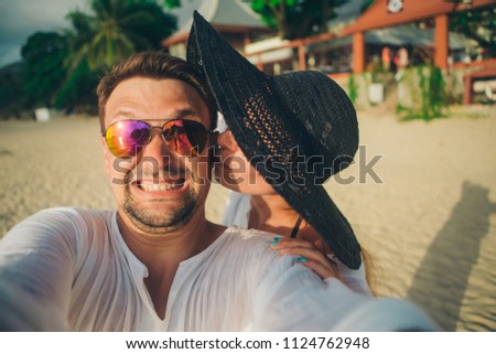 Portrait of a man and a woman: a couple takes a selfie on the beach. Husband and wife on vacation. girl kesses guy