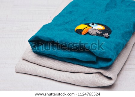 fabric texture as background. Blue and grey flax. Item of clothing close-up. bird Toucan made of beads and a lightning strike.. Symbol on blue background