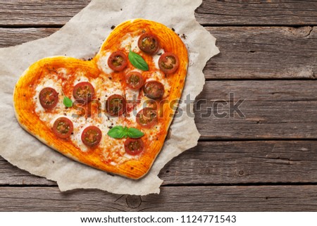 Heart shaped pizza with tomatoes and mozzarella. Valentines day greeting card. Top view with space for your text