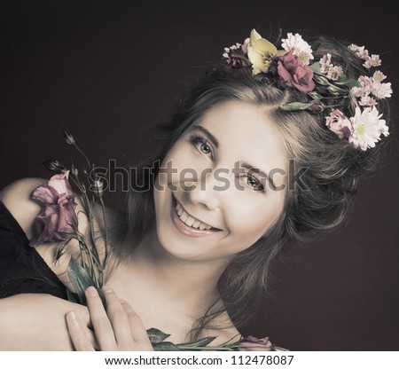 Happy girl with flowers in her hair and in her hands