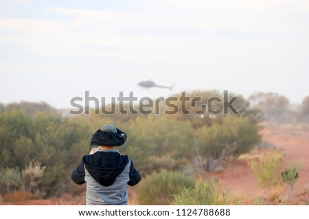 Finke, Northern Territory, Australia - June 9, 2018: Tatts Finke Desert Race observer trackside with race helicopter overhead.