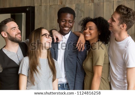 Happy multiracial millennial friends posing for picture at friendly meeting in coffeeshop, smiling diverse students standing laughing at funny joke, having fun together in cafe. Ethnicity concept