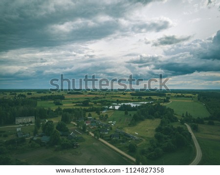 drone image. aerial view of rural area with houses and roads under heavy rain clouds in summer day. latvia - vintage retro look
