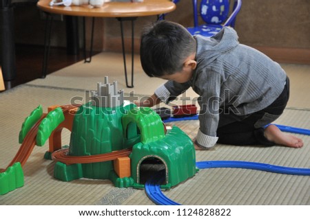 asian little boy playing railroad train toy 