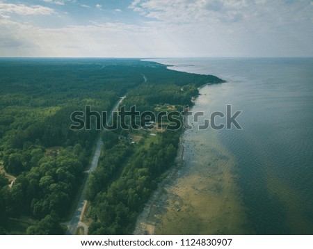 drone image. aerial view of Baltic sea shore with rocks and forest on land and highway near water. Latvia beach - vintage retro look