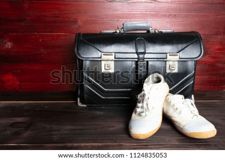 Schoolbag with white sneakers on wooden floor 