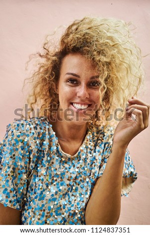 Portrait of an attractive female with blonde curly hair smiling and looking at camera