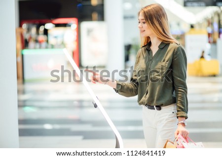 woman wearing casual clothes going shopping. Looking on information board with map of mall