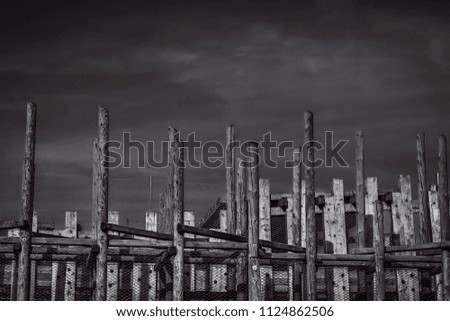 abstract design from big wooden columns against the background of the cloudy storm sky