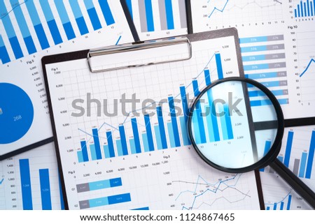 Analyzing and gathering statistical data. Growth charts. Many business reports and magnifying glass.
 Royalty-Free Stock Photo #1124867465