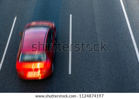 Red car runs fast in the highway by the left lane at sunset. Top view and copy space in the right side.
