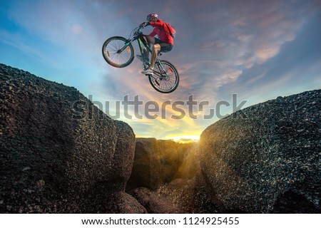Professional rider is jumping on the bicycle, with background of sunset, racing in high speed competition Royalty-Free Stock Photo #1124925455