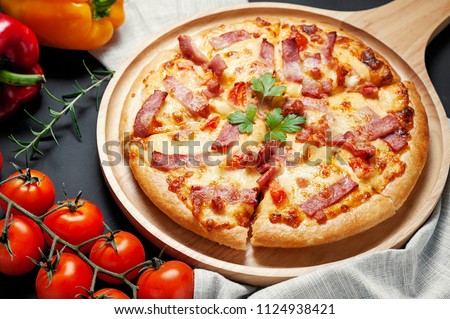 Delicious Italian pizza sliced ham, bacon and cheese with food ingredients on old kitchen table.