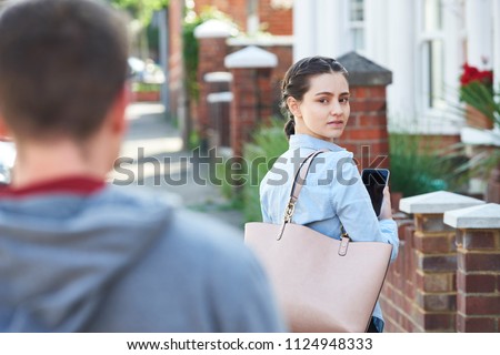 Young Woman Texting For Help On Mobile Phone Whilst Being Stalked On City Street Royalty-Free Stock Photo #1124948333