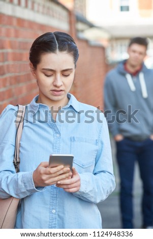 Young Woman Texting For Help On Mobile Phone Whilst Being Stalked On City Street Royalty-Free Stock Photo #1124948336