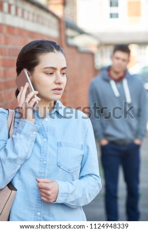 Young Woman Calling For Help On Mobile Phone Whilst Being Stalked On City Street Royalty-Free Stock Photo #1124948339