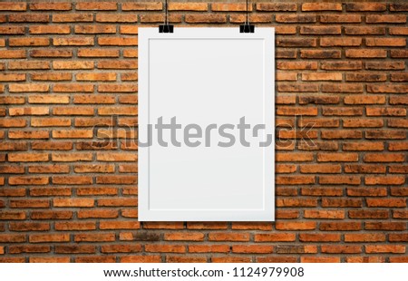 White poster Or a white frame hanging on the brick wall background in the room.