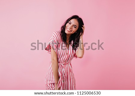 Spectacular latin young woman playing with her brown hair. Indoor photo of wonderful female model isolated on pink background.