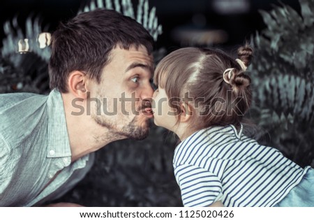 Dad kisses a small daughter at a table in a cafe, celebrating his father's day, family values
