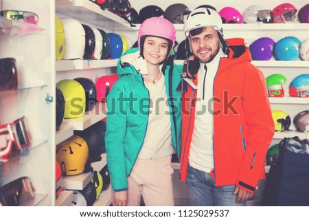 Glad young couple in skiing outfit satisfied with choice in modern store of sports equipment
