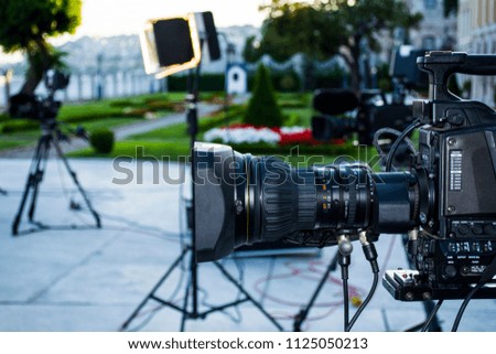 television shooting in a public park. Movie shooting camera or video production and film, tv crew team with camera, light and audio equipment at outdoor location