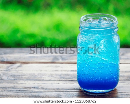 Round spoon filled with soda water, Hawaiian Blue, put on the table with fresh green nature.