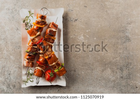 Grilled skewers with sausage, bacon and vegetables. Top view. stone background. 