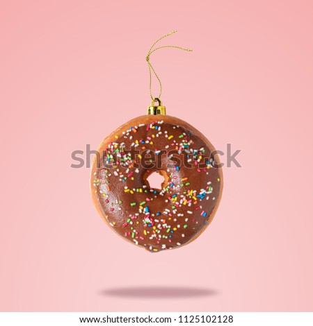 Christmas bauble decoration made of chocolate doughnut on pink background. Minimal concept. Royalty-Free Stock Photo #1125102128