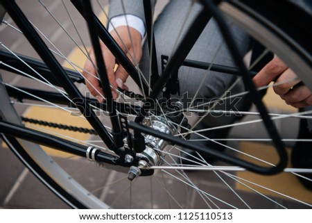 cropped view of businessman repairing bicycle wheel