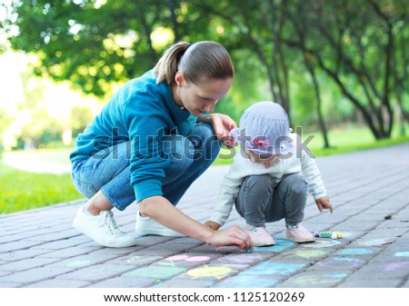 mother and her child is drawing crayons in the park.