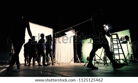 Behind the scenes of TV commercial movie film or video shooting production which crew team and camera man setting up green screen for chroma key technique in big studio.