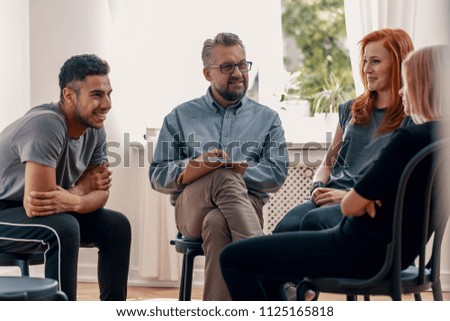 Smiling spanish man talking to his friends during meeting for teenagers with therapist Royalty-Free Stock Photo #1125165818