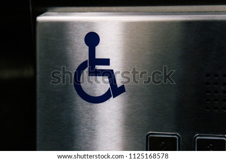 Disabled person symbol on silver elevator. Blue wheel chair sign.