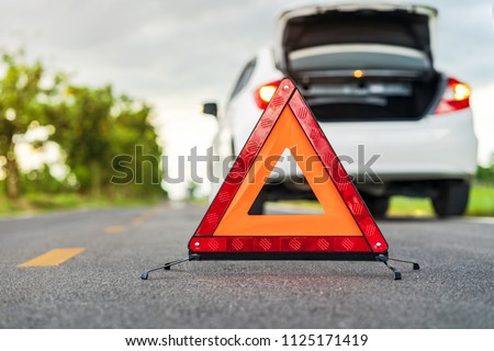 Problems car and a red triangle warning sign on the road