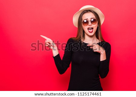 Woman showing pointing on red background. Very fresh and energetic beautiful young girl smiling happy presenting on red background.