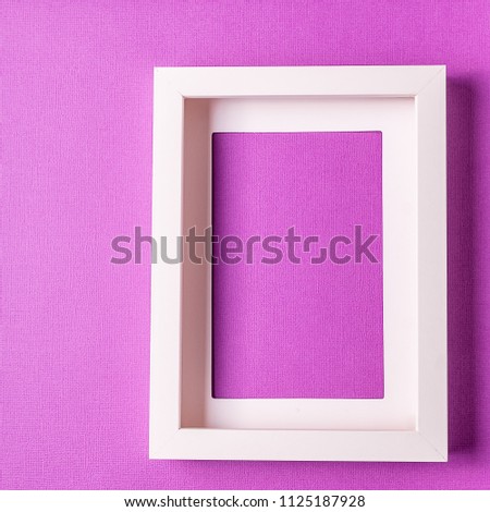 Minimalism style. White empty picture frame against; abstract colored paper background; flat lay, vertical.