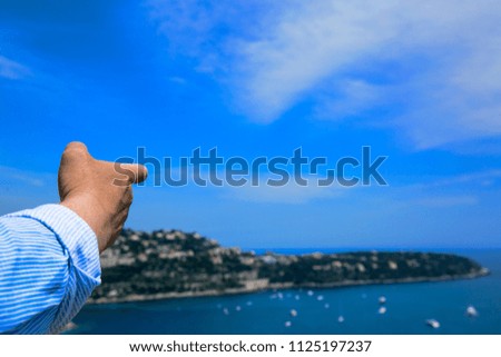 The hand of a man pointing into the distance to a beautiful view ahead