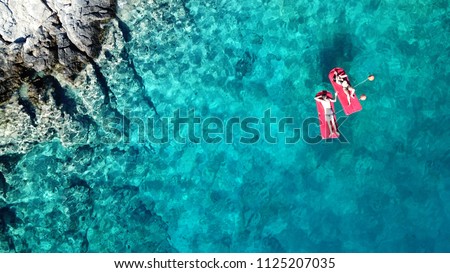 Aerial drone bird's eye top view of couple sitting in inflatable matress in rocky emerald water tropical caribbean resort